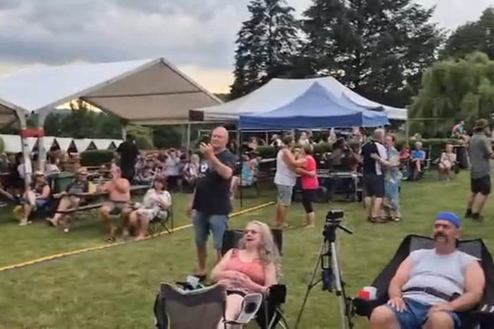 Publikum sedící a tleskající pod stany